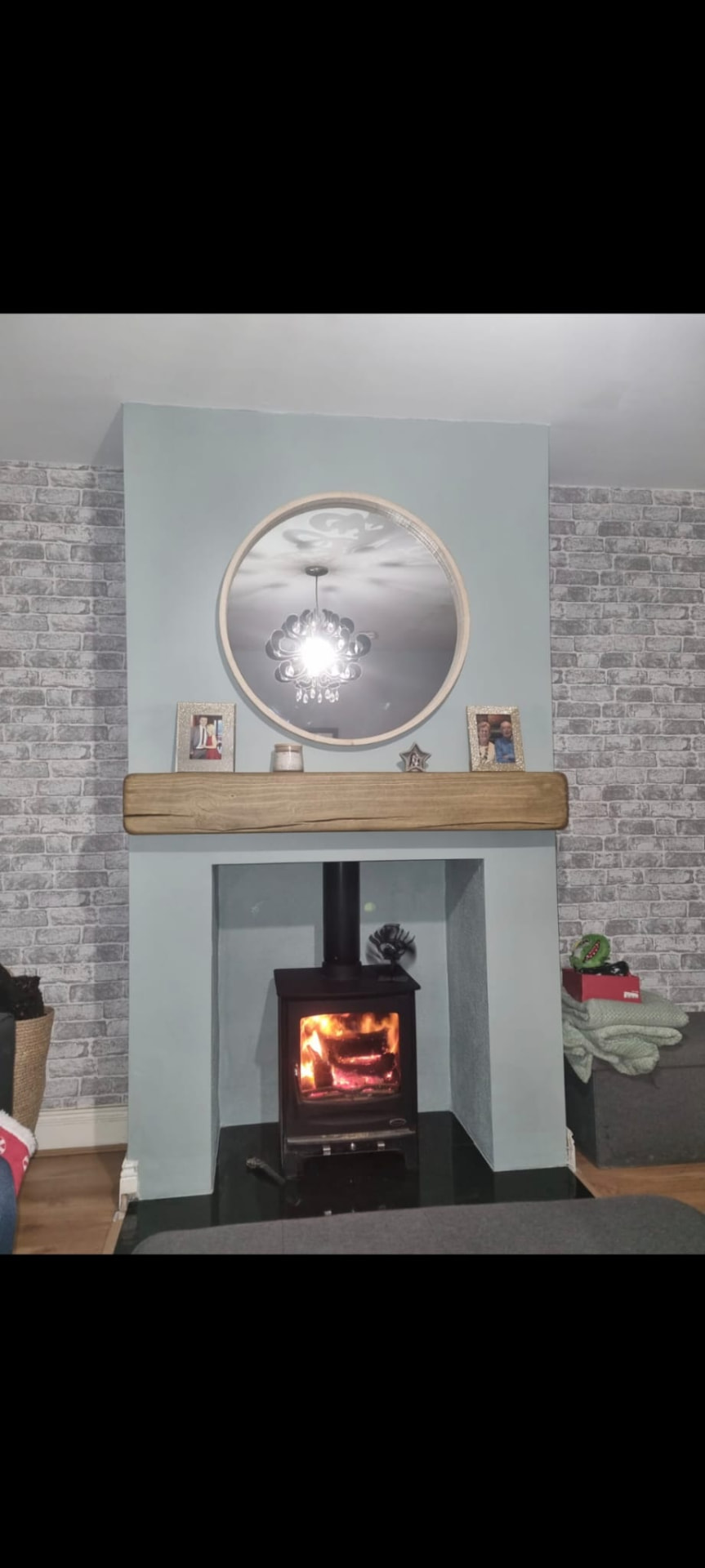 New stove lit in a rebuilt chimney breast with oak beam mantel and granite hearth
